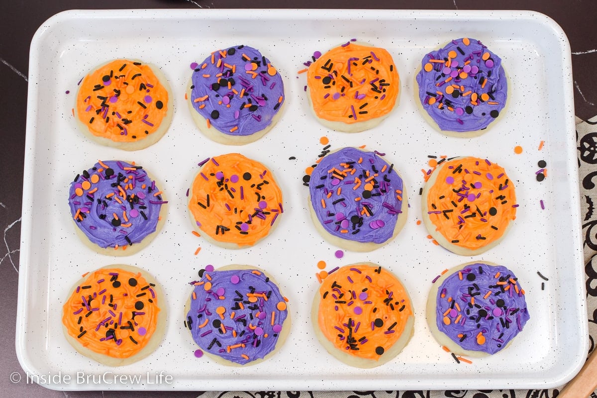 A white baking sheet with frosted sugar cookies on it.