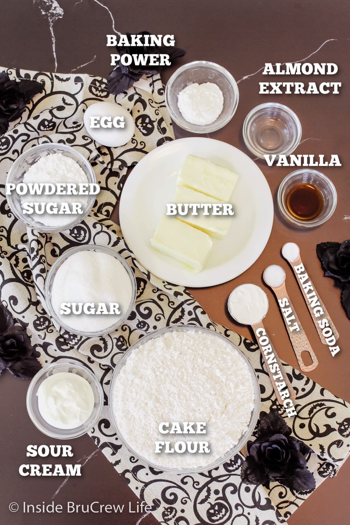 A dark board with bowls of ingredients needed for sugar cookies.