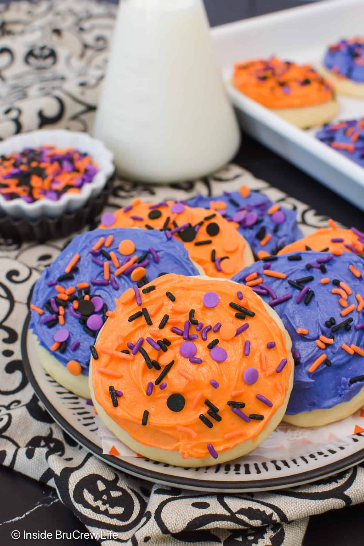 Orange and purple frosted sugar cookies on a plate.