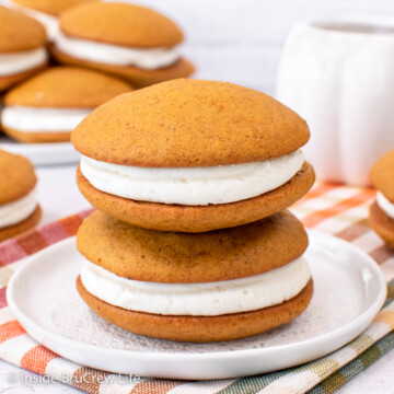 Two pumpkin cookies filled with maple frosting on a white plate.