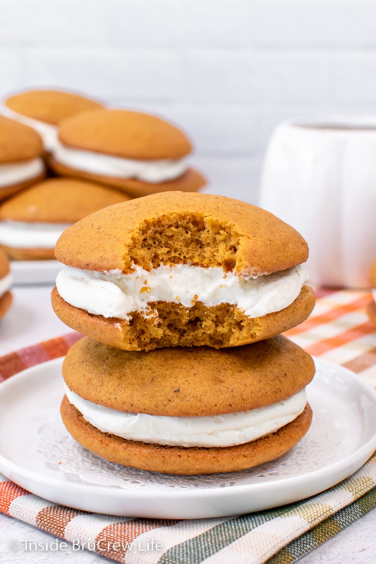 Two pumpkin whoopie pies with a bite out of one.