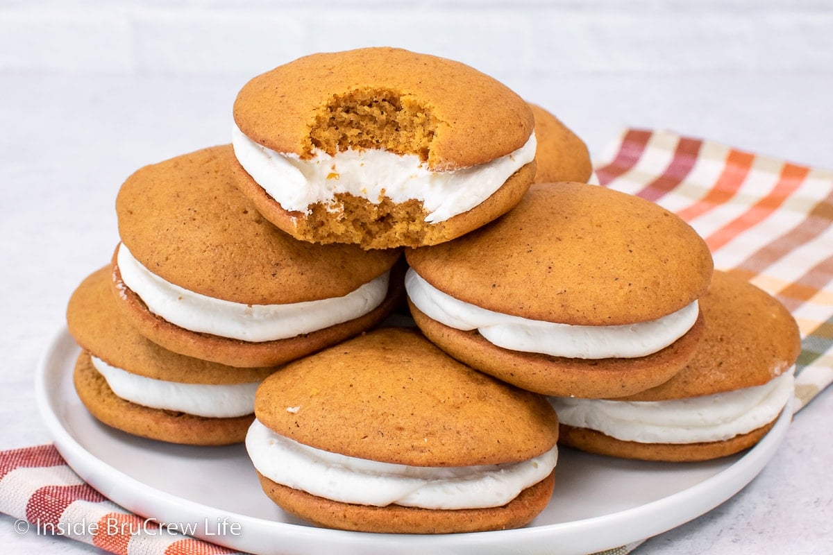 A white plate with a stack of filled pumpkin cookies.