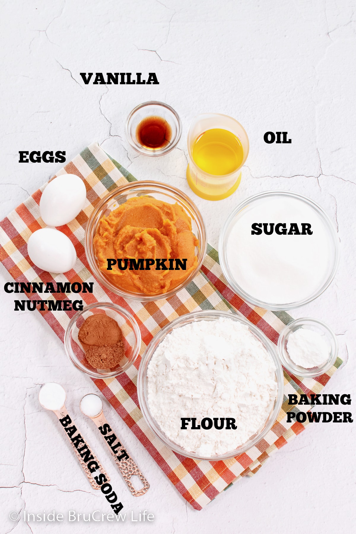 A white board with bowls of ingredients to make pumpkin cookies.