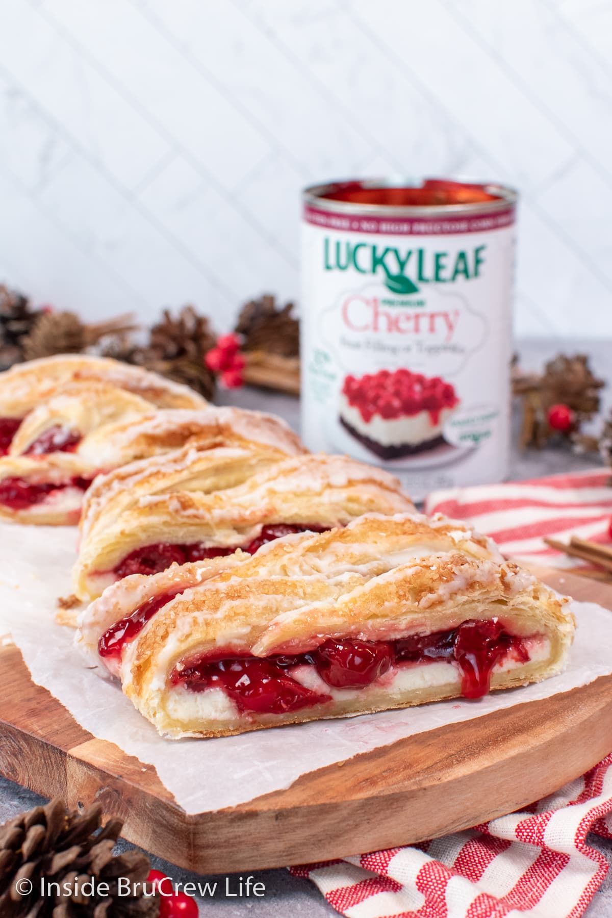 A wooden board with slices of cherry cream cheese danish on it.