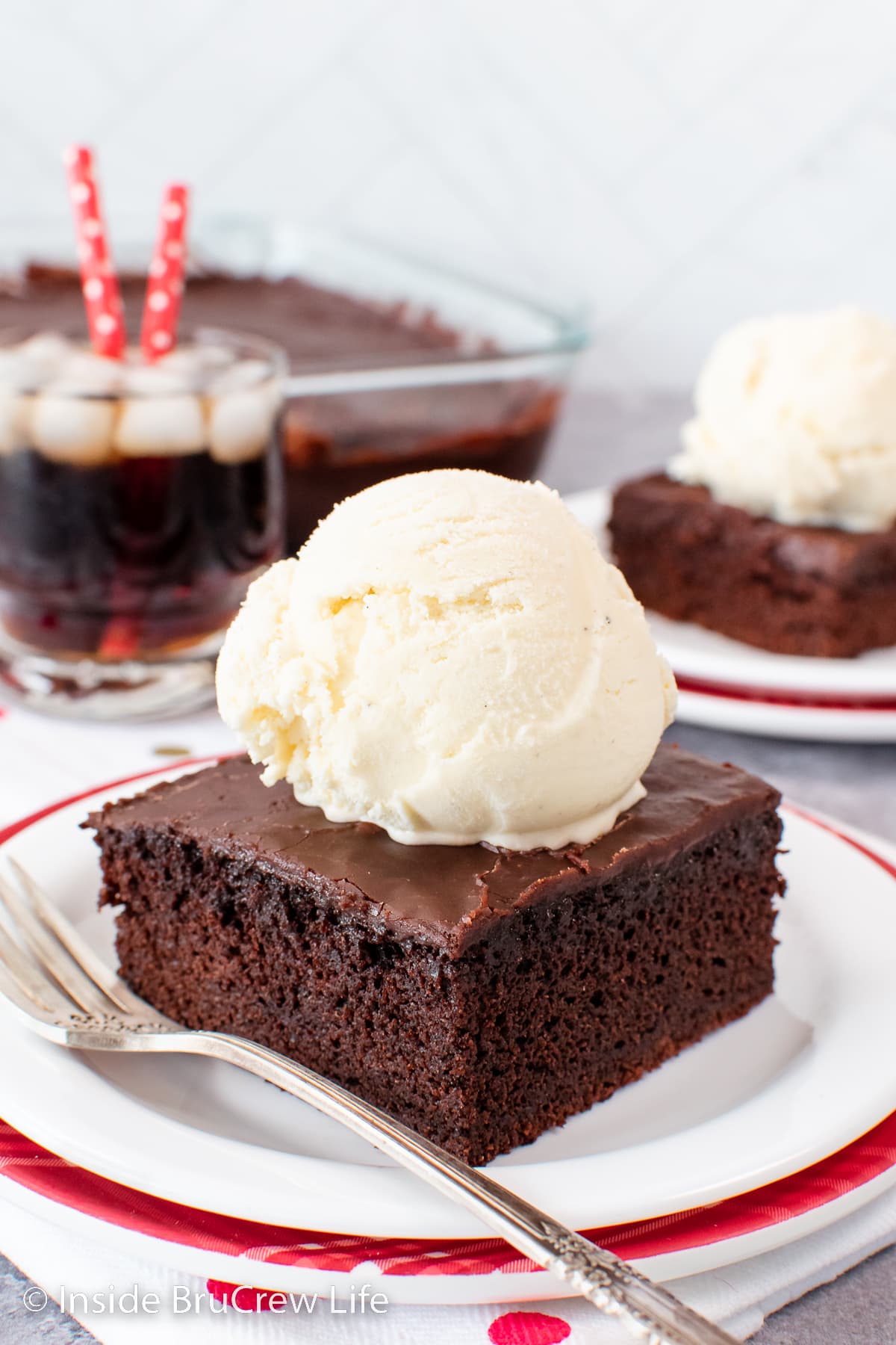 A piece of chocolate cake topped with vanilla ice cream on a white plate.