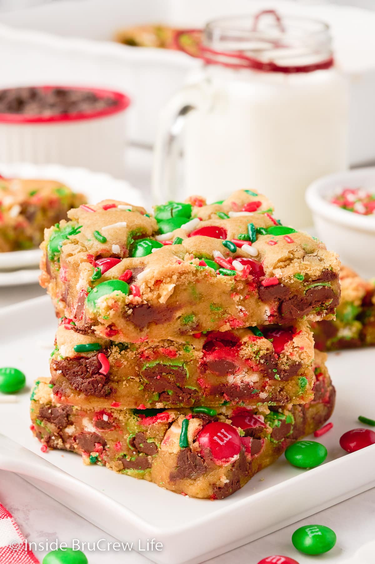 A stack of three blonde brownies filled with red and green candies.