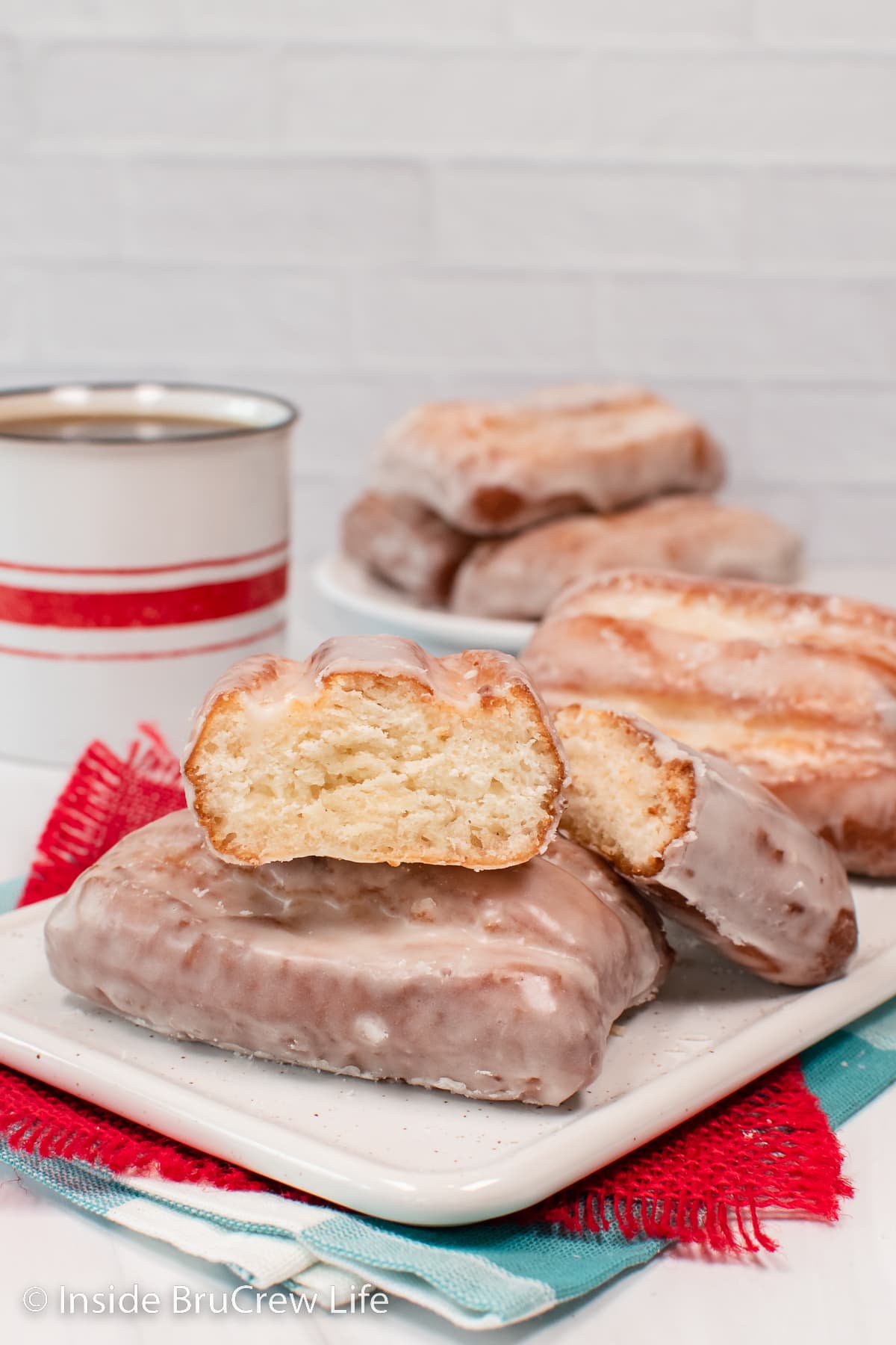Fluffy glazed donut sticks stacked on a plate.