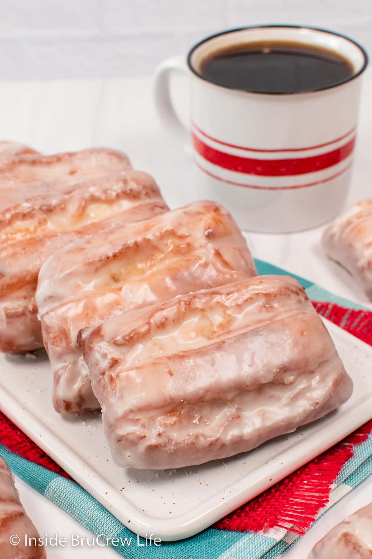 Glazed donuts stacked on a white plate.