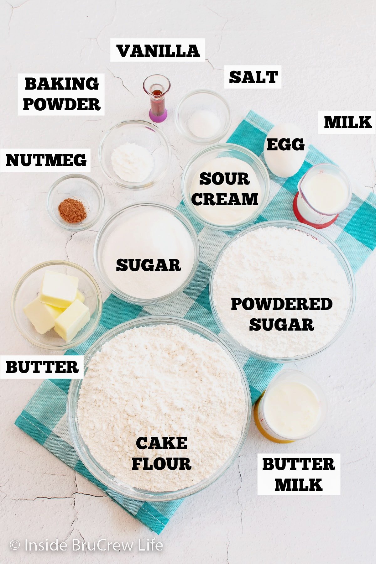 A white board with bowls of ingredients for making fried donuts.