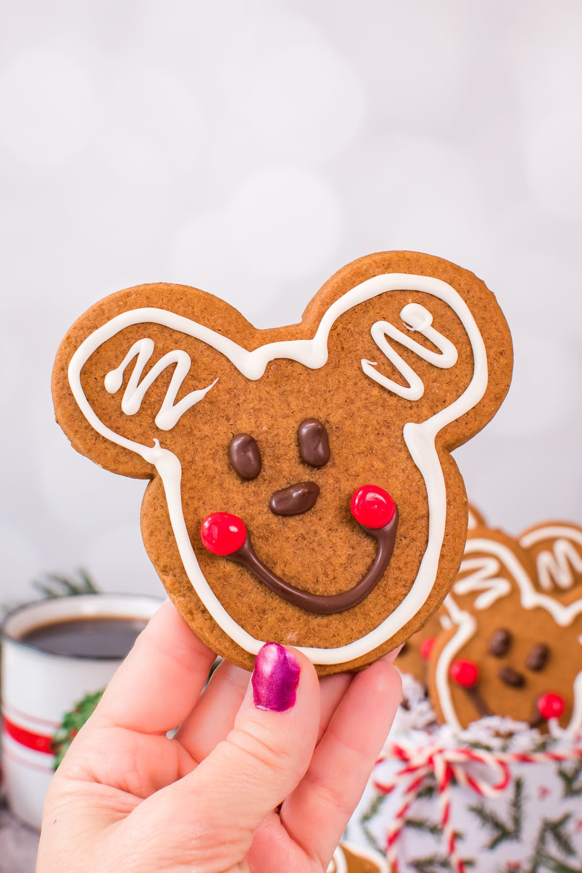 A hand holding a Mickey gingerbread cookie in the air.
