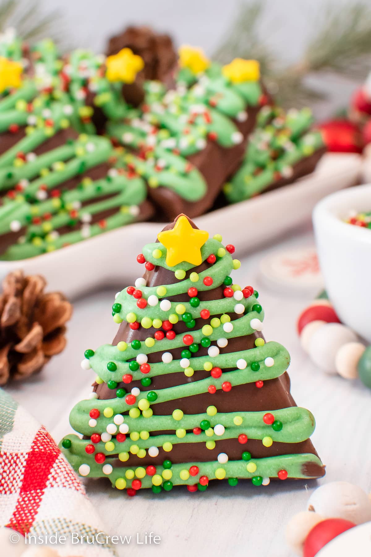 A decorated peanut butter Christmas tree standing on a white board.