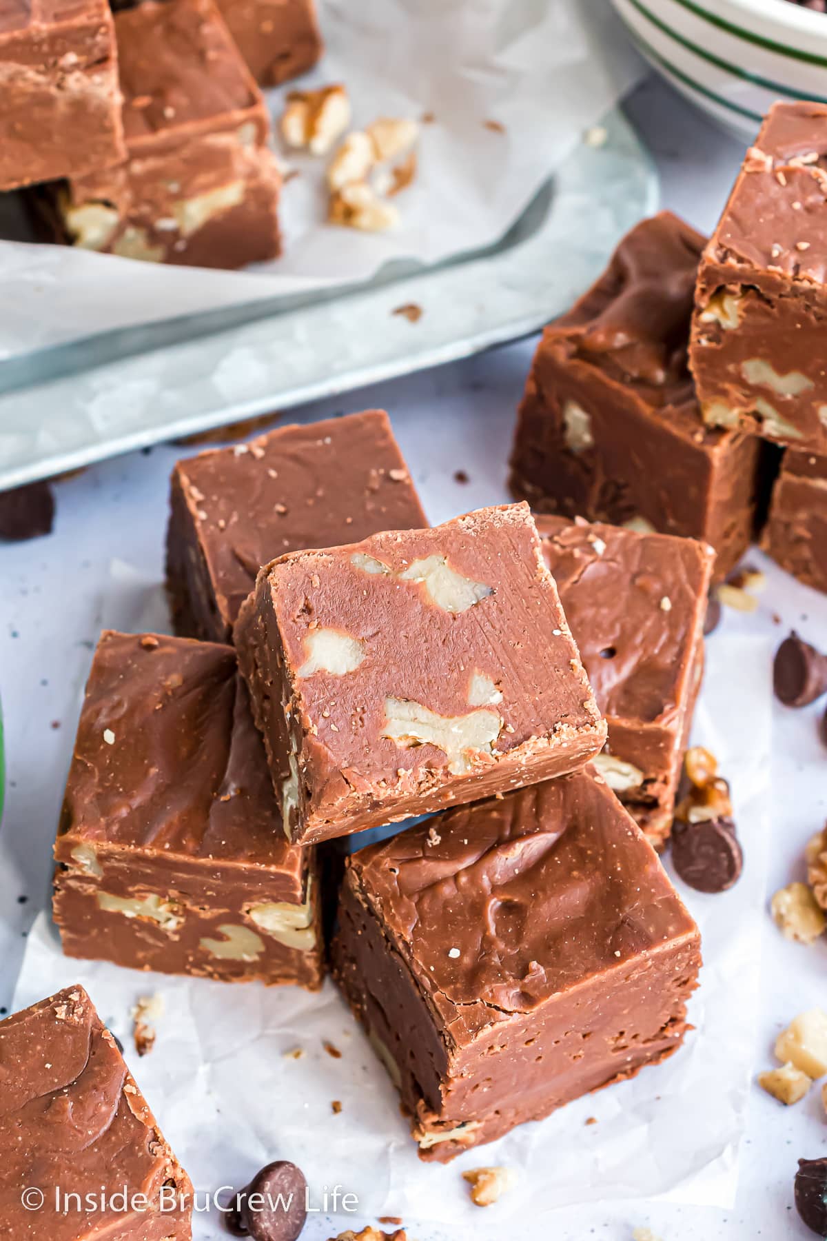 A pile of chocolate fudge made with walnuts on a white paper.