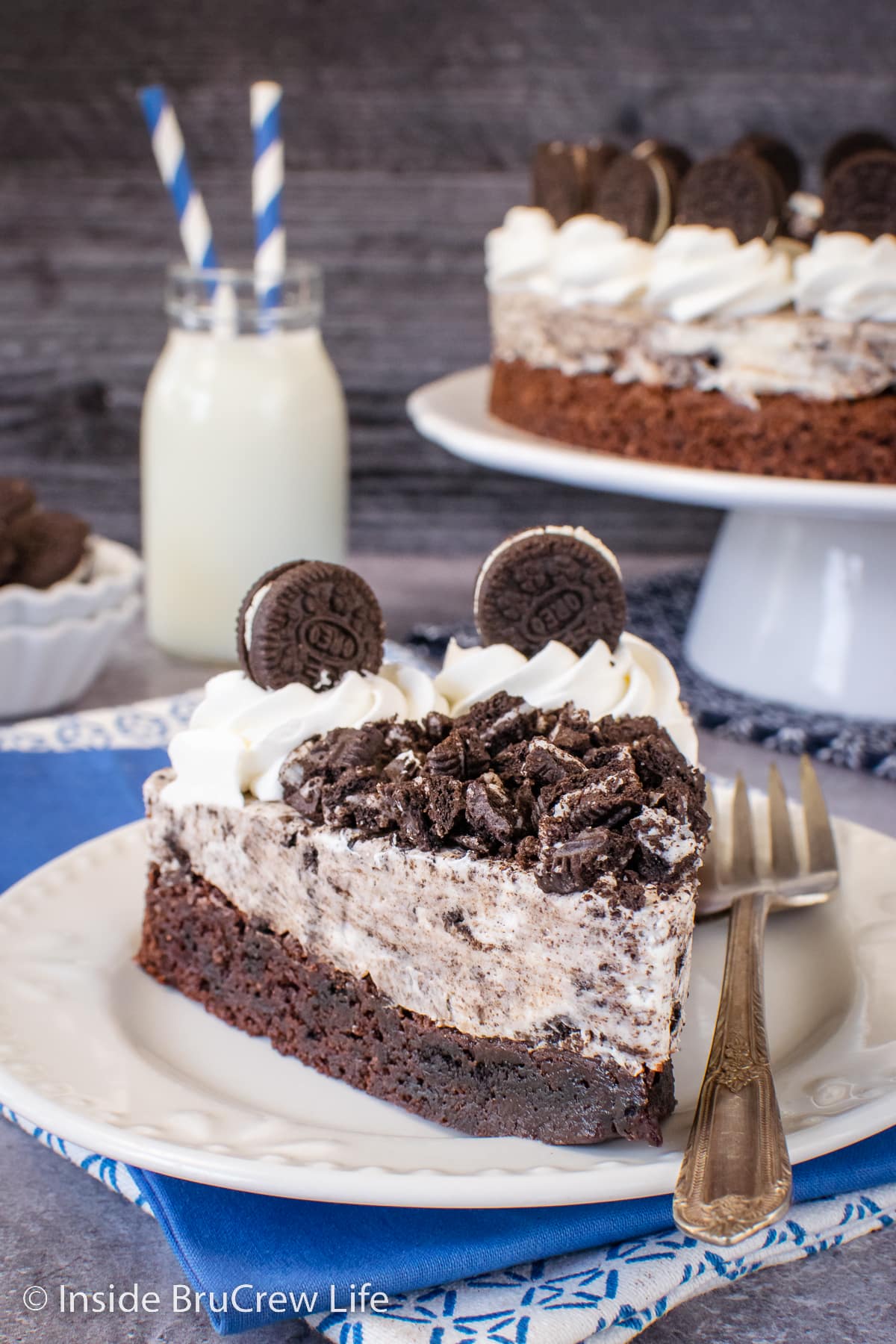 A slice of brownie cake topped with Oreo mousse on a white plate.