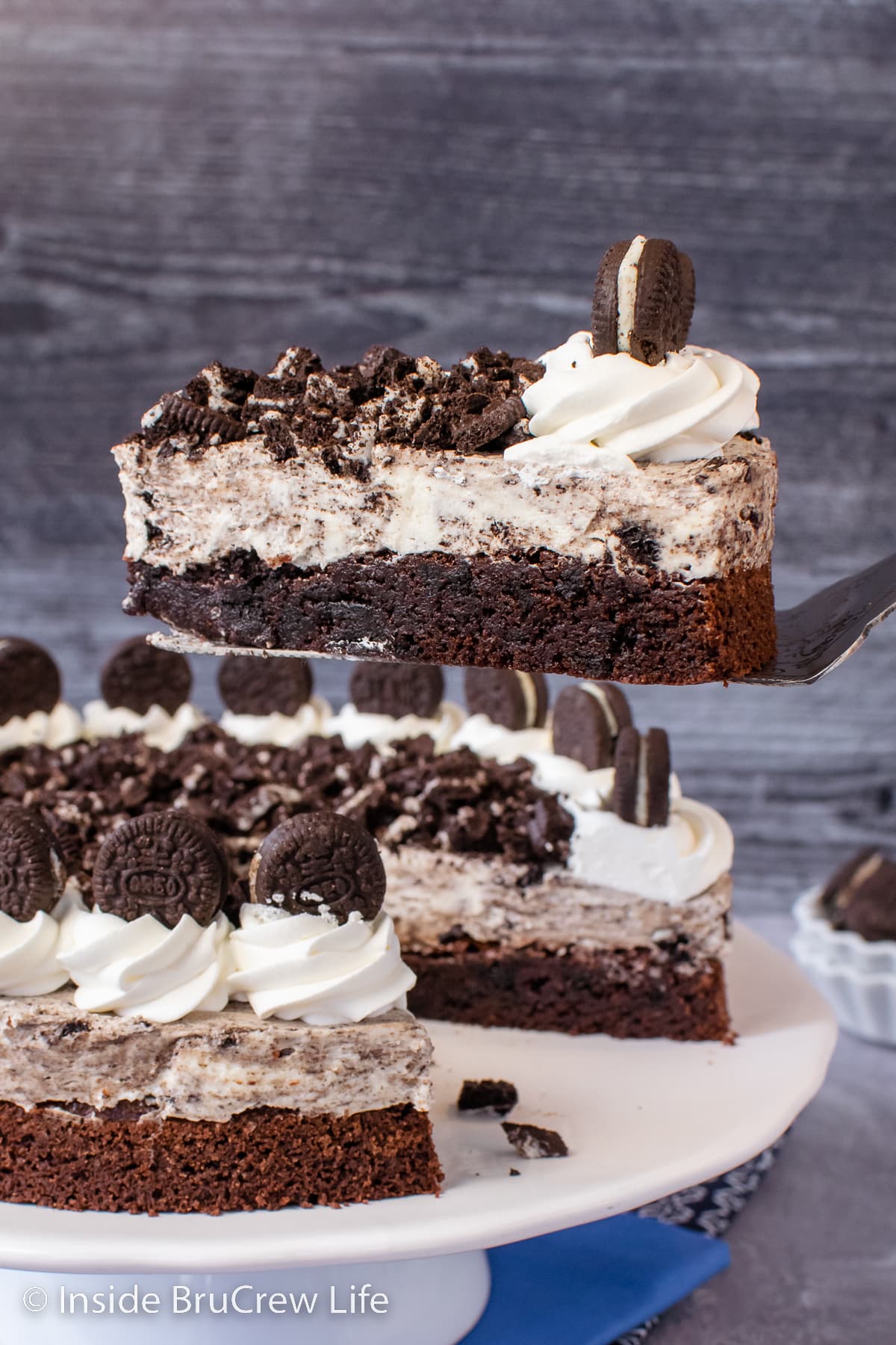 A slice of Oreo brownie cake being lifted out of a full cake.
