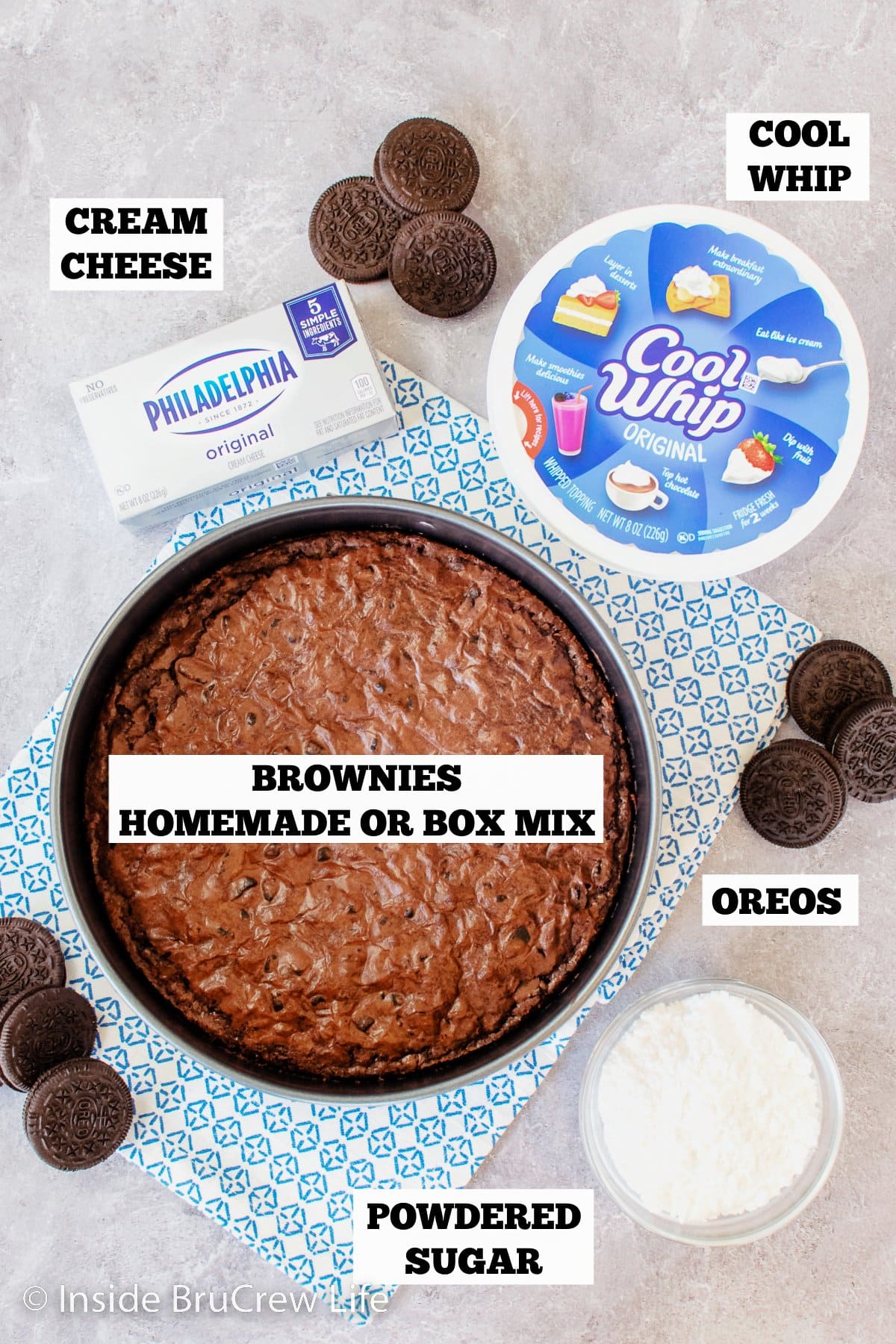 A gray board with bowls of ingredients for a brownie mousse cake.