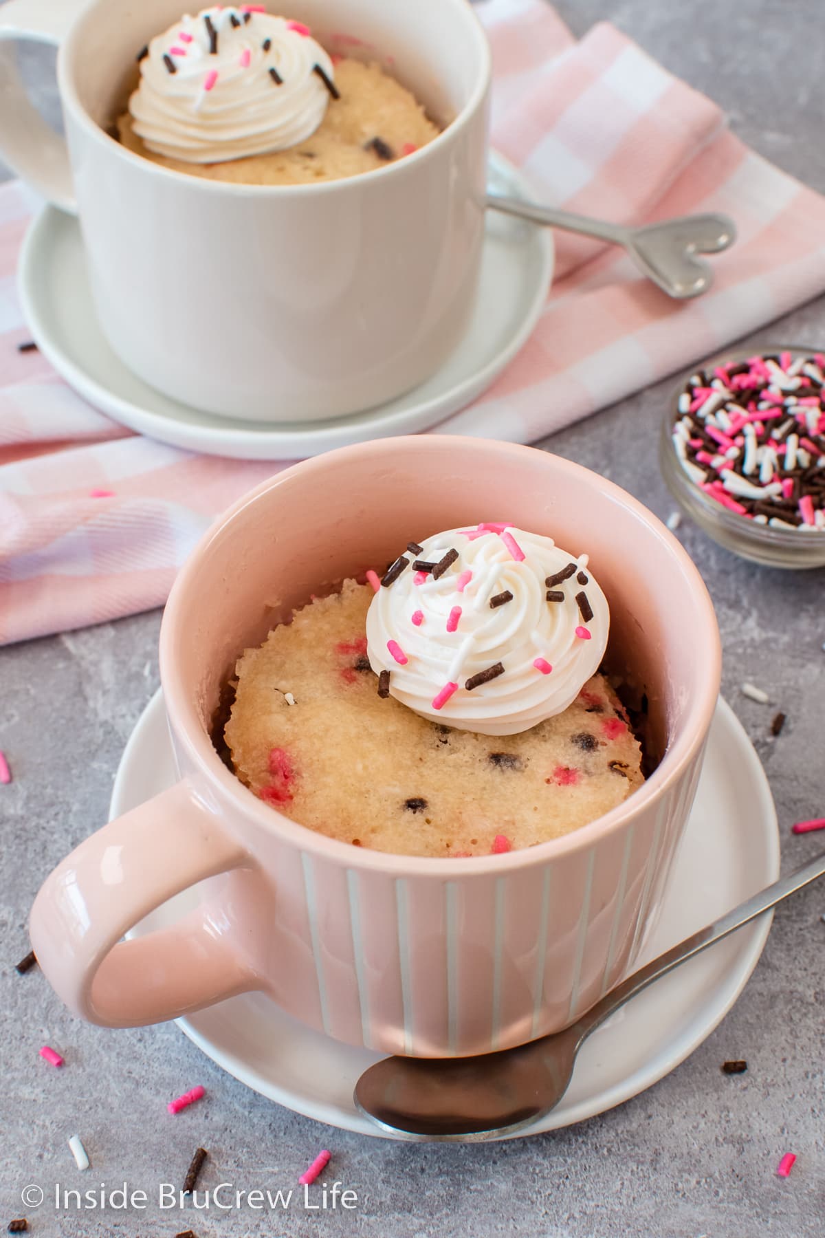 A pink cup with a sprinkle cake in it.
