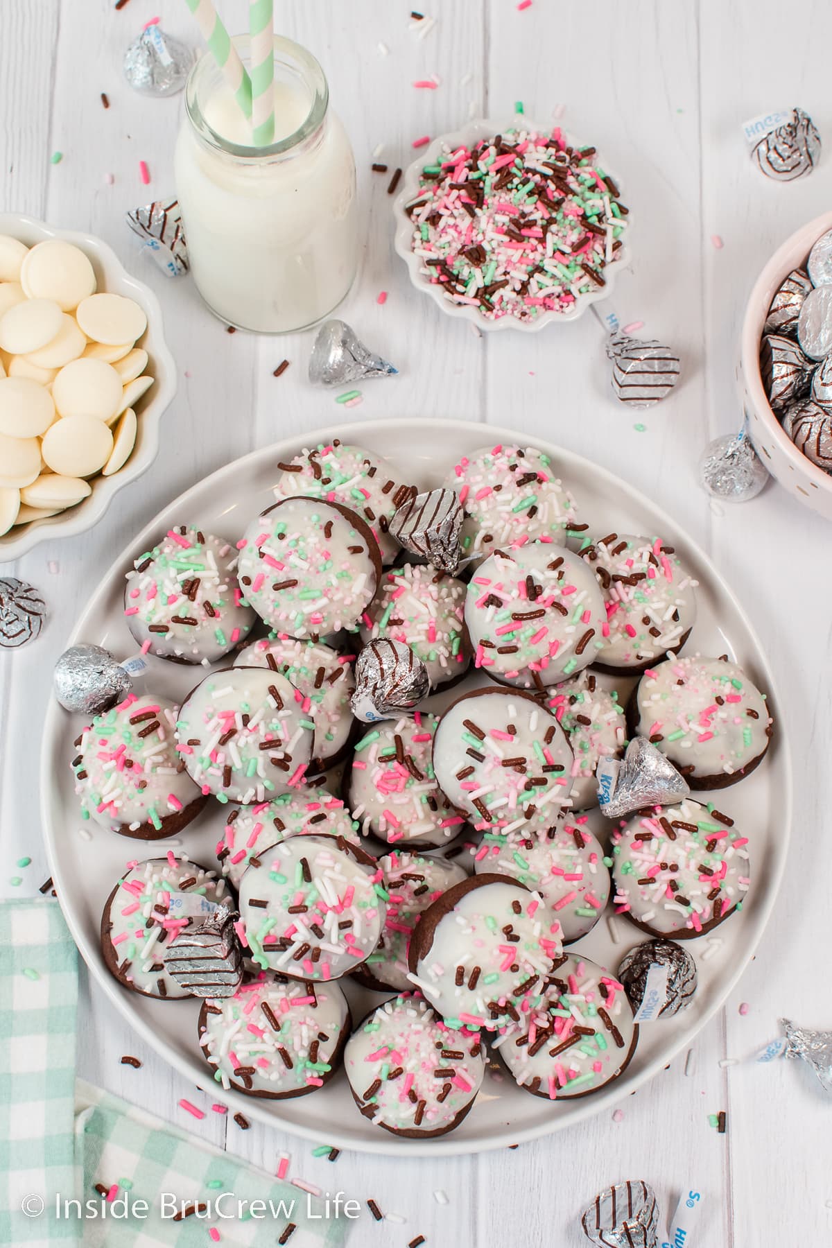 A white plate with chocolate dipped bon bon cookies stacked on it.