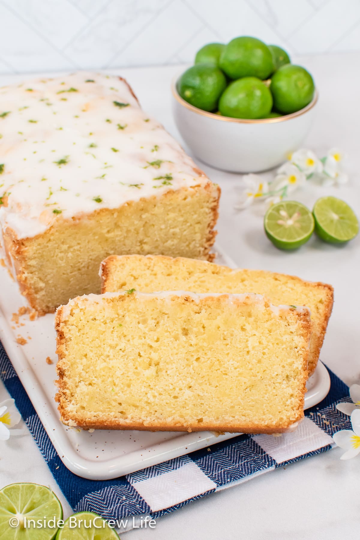 Slices of glazed pound cake and the loaf on a white plate.