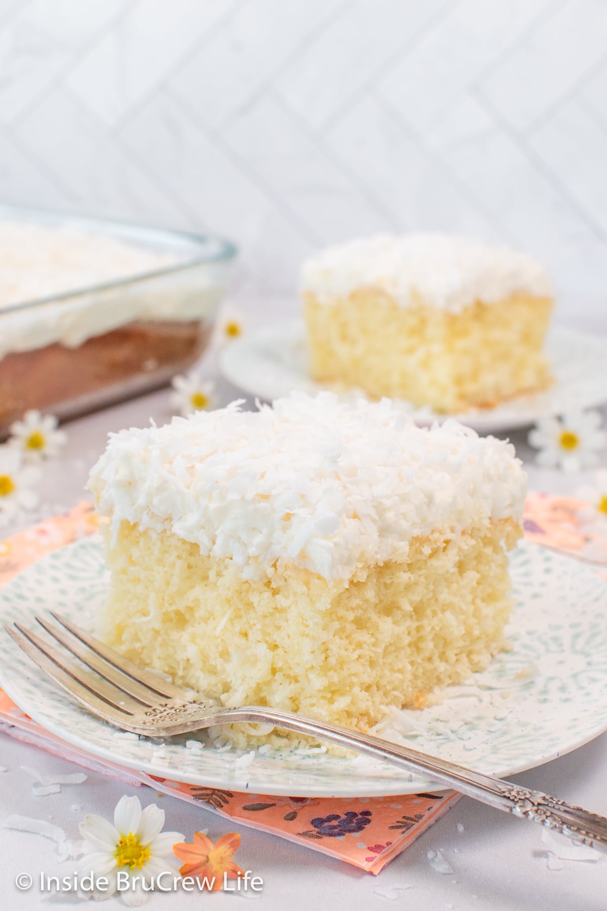 Two plates with fluffy white cake topped with frosting on them.