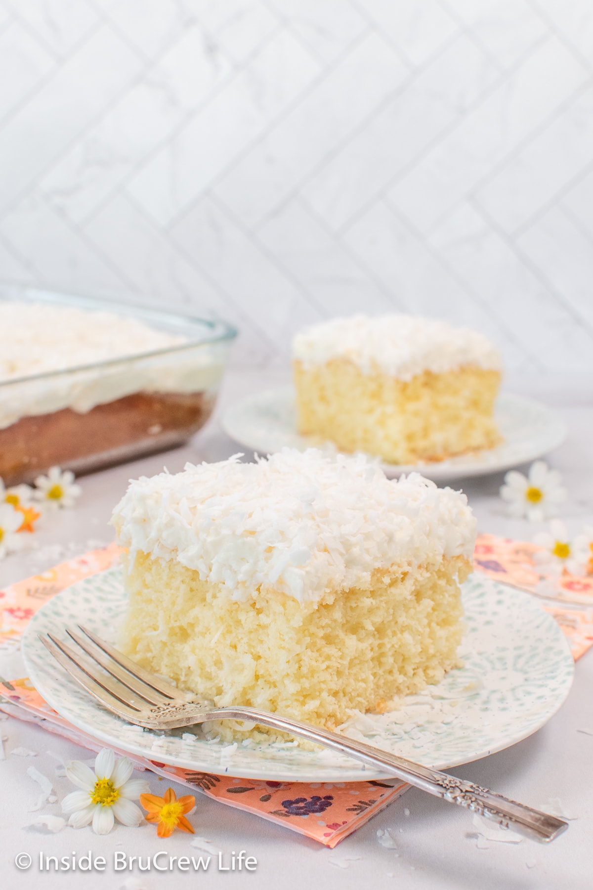 Two plates with fluffy white cake topped with frosting on them.