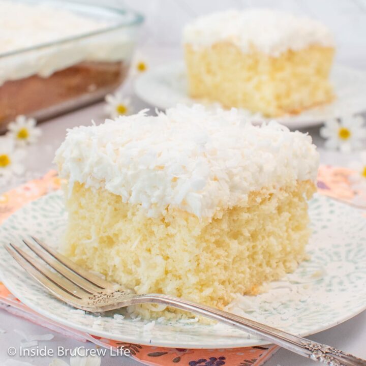 A white plate with a square of fluffy white cake with frosting on it.
