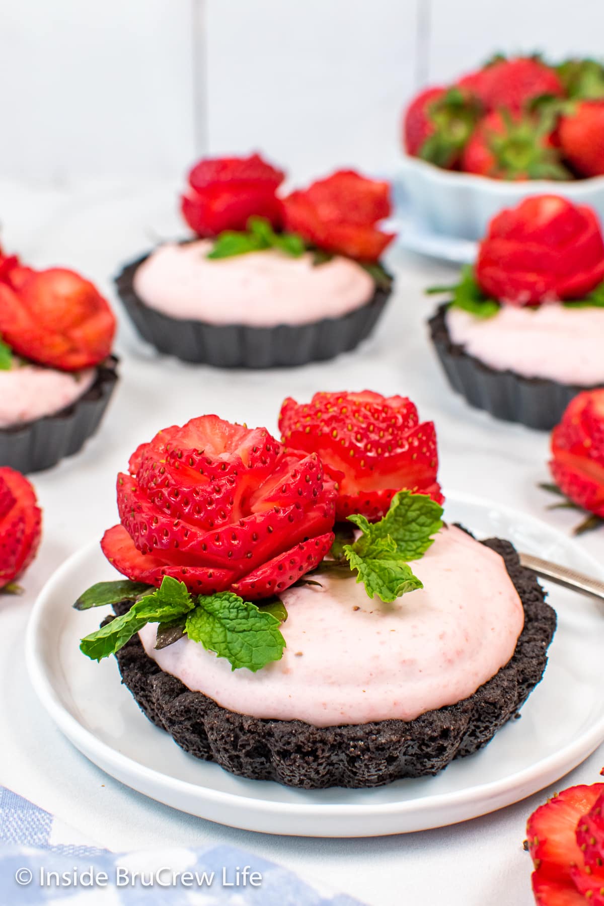 Strawberry tarts with Oreo crusts on white plates.