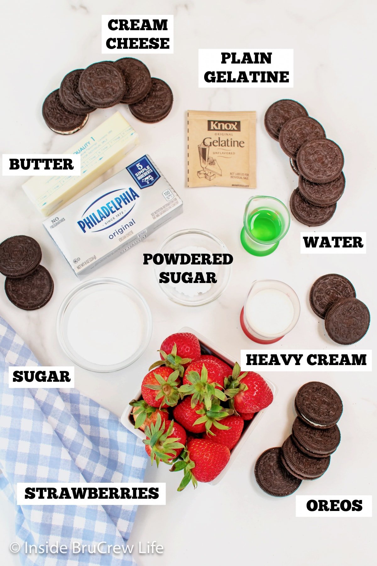A white board with bowls of ingredients needed to make mini strawberry Oreo pies.