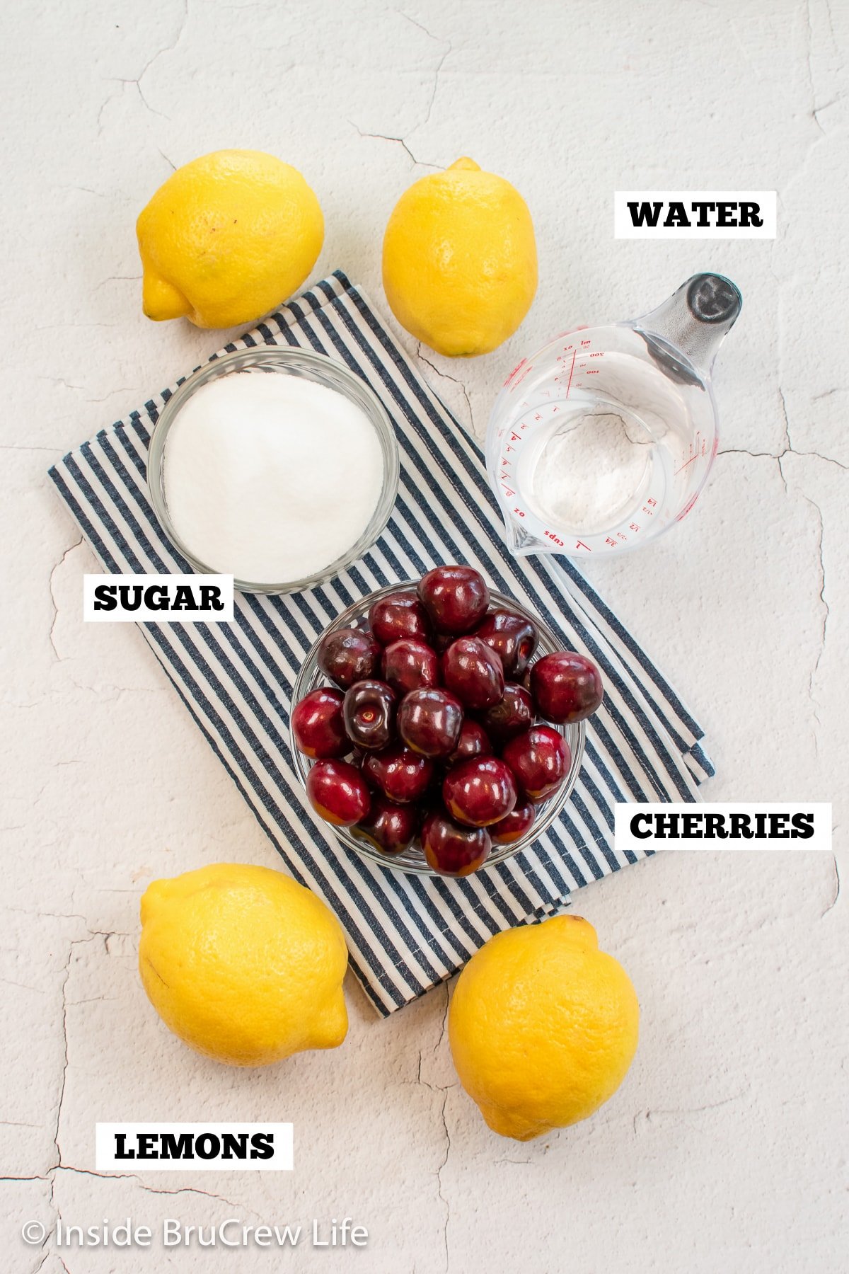 A white board with ingredients needed to make lemonade with cherries.