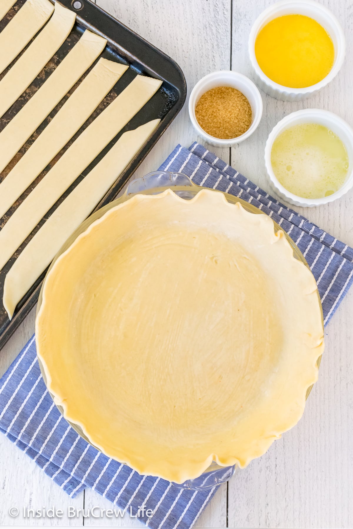 One pie crust in a pie pan and one cut into strips.