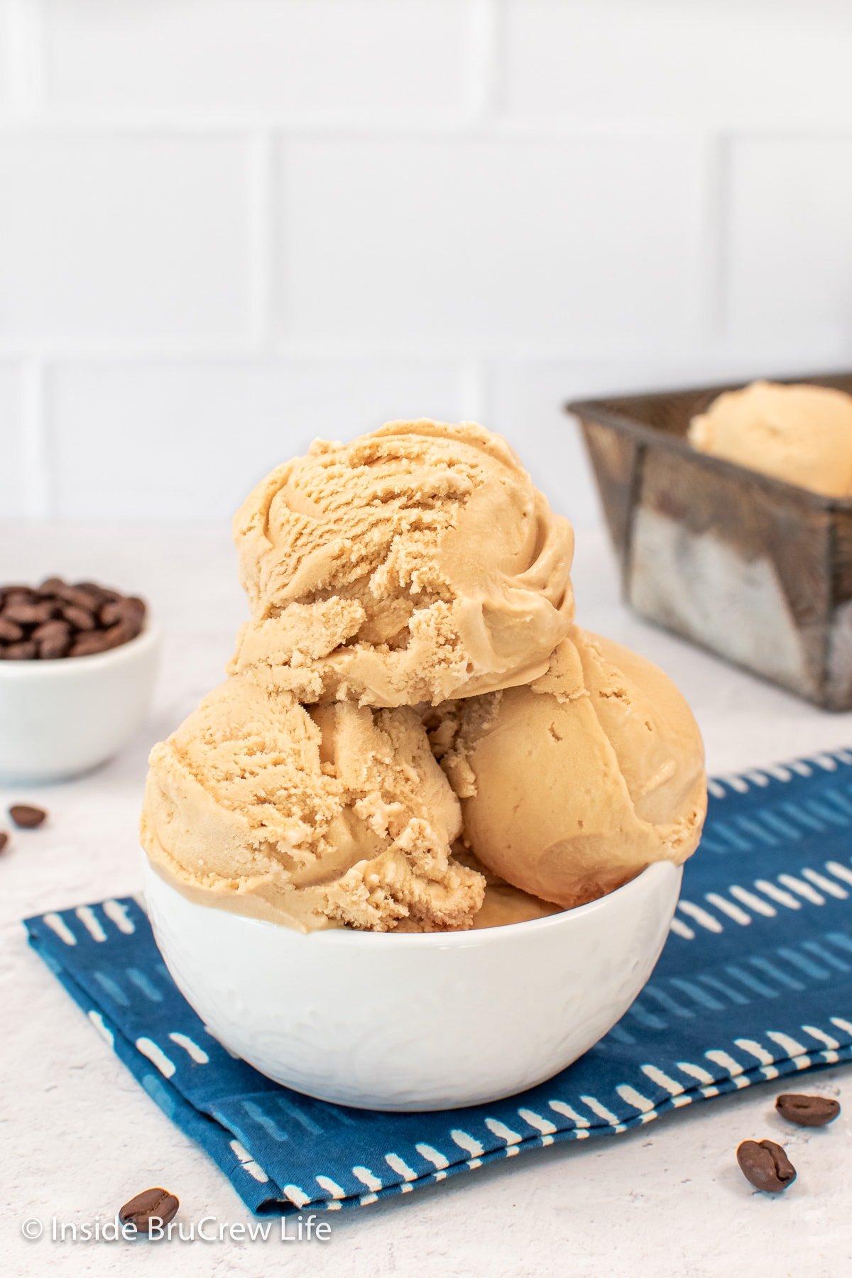 A white bowl with three large scoops of ice cream in it.