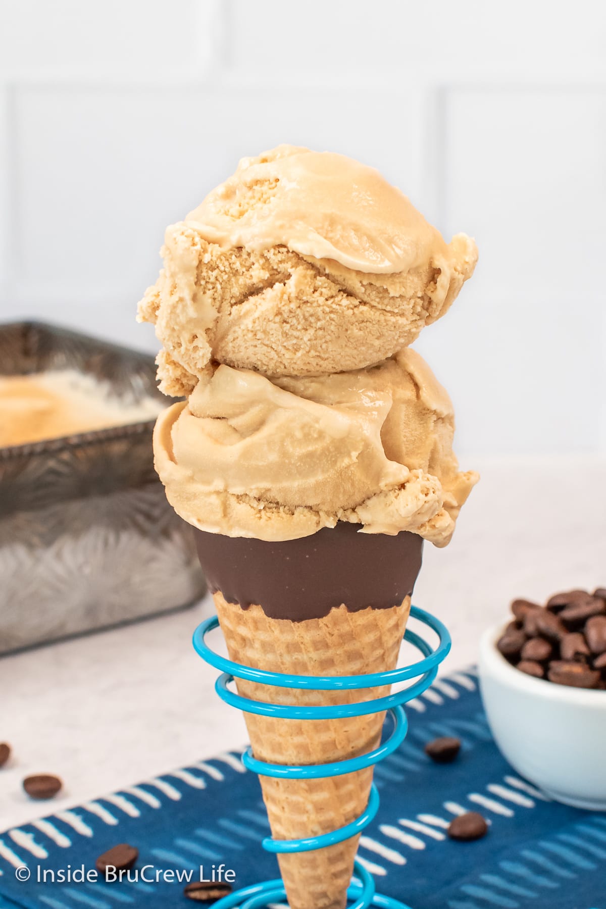 A sugar cone with two scoops of ice cream in it.