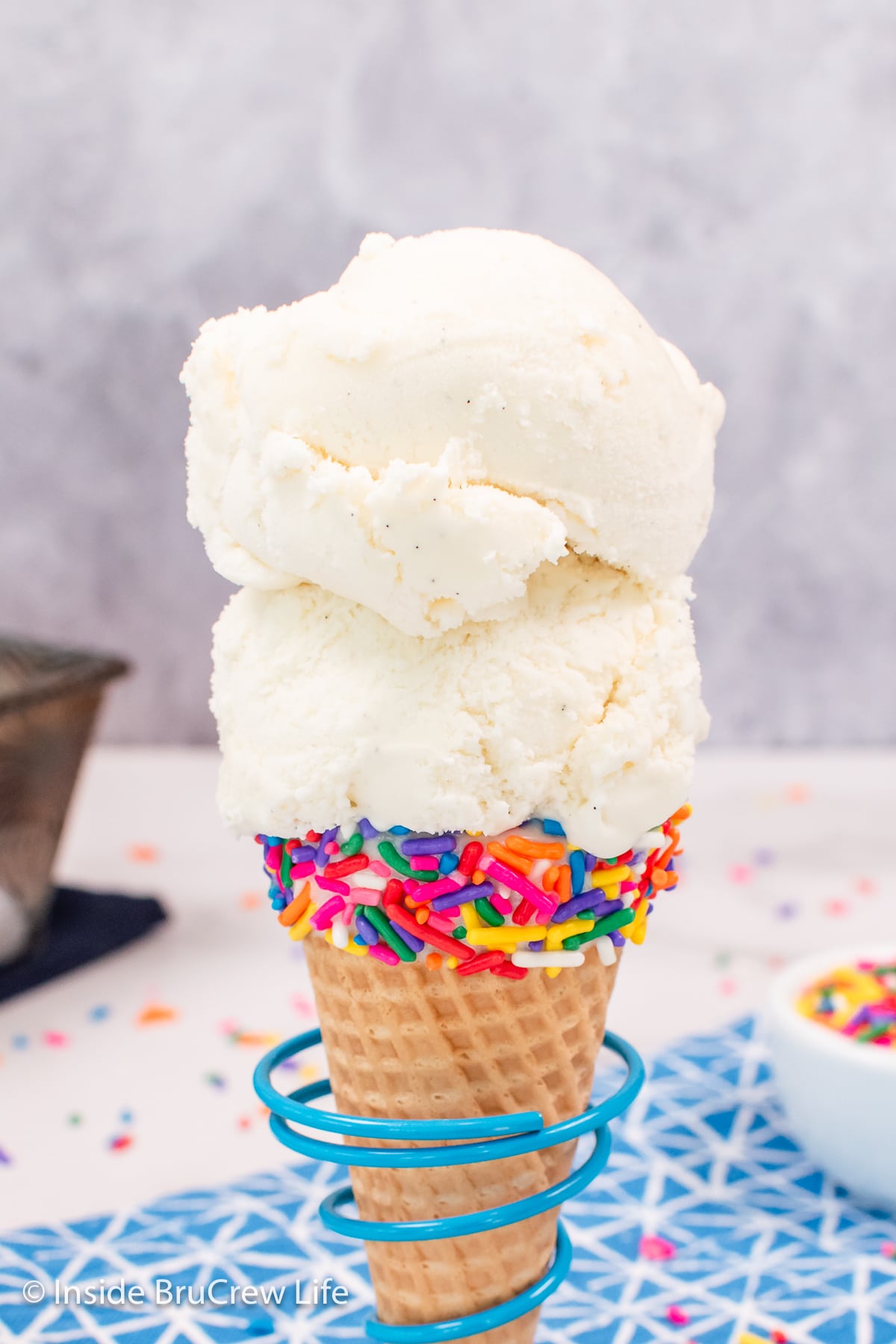 Two scoops of ice cream on a cone with sprinkles.