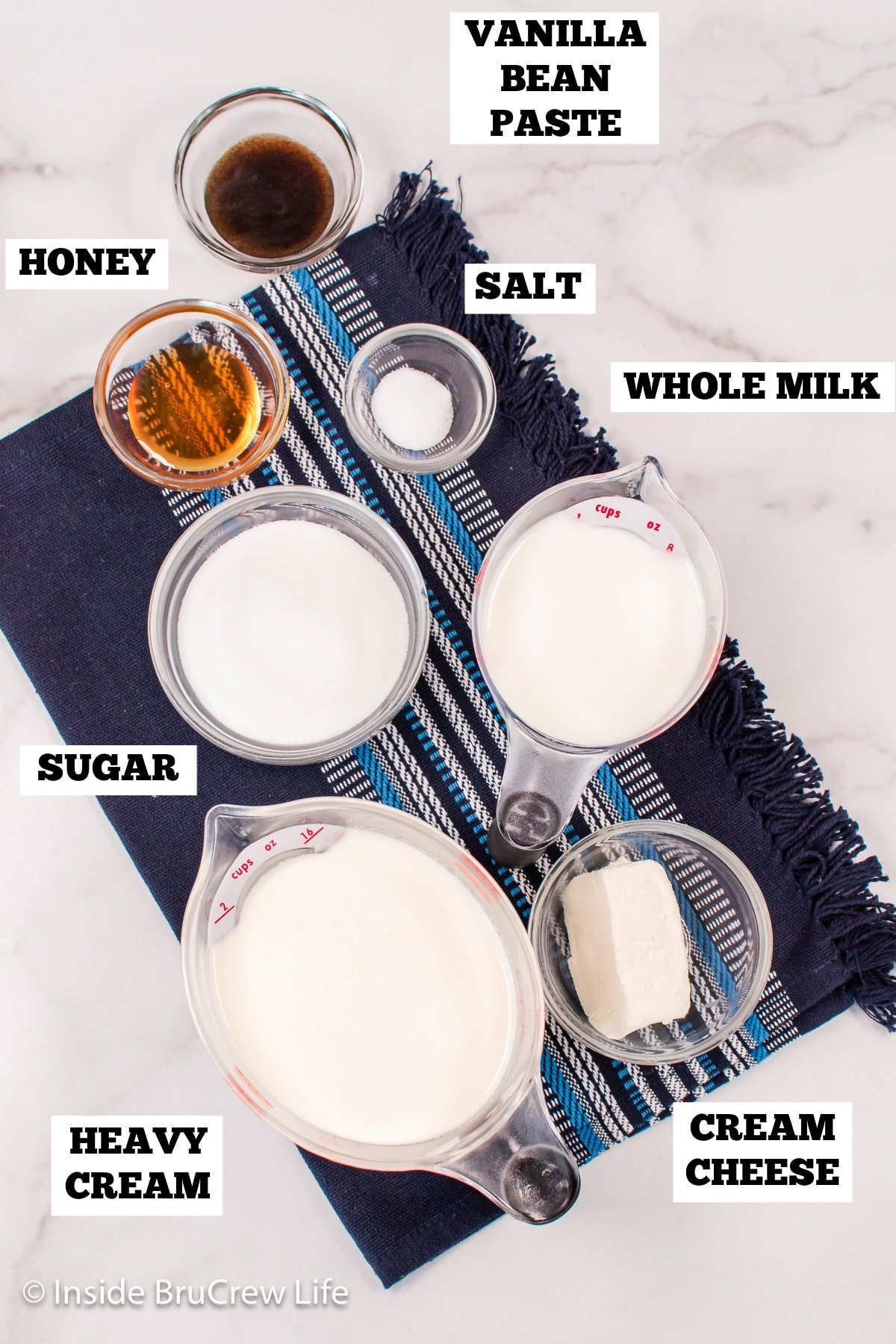 A white board with bowls of ingredients needed to make homemade vanilla ice cream.