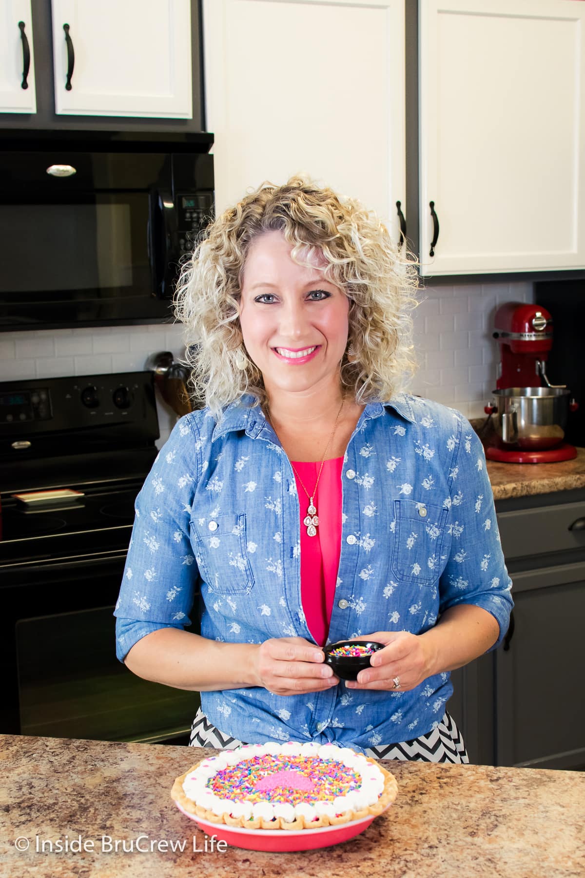 A girl standing in a kitchen with a pie.