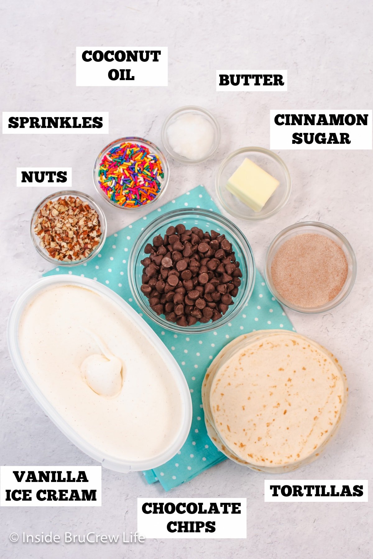 A white board with bowls of ingredients needed to make dessert tacos.