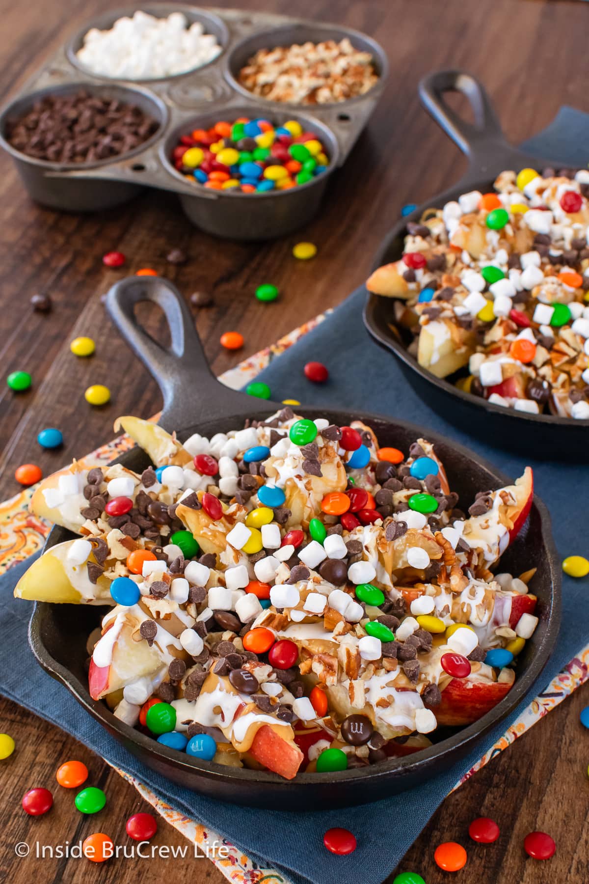 Two pans filled with apples and loaded with toppings.
