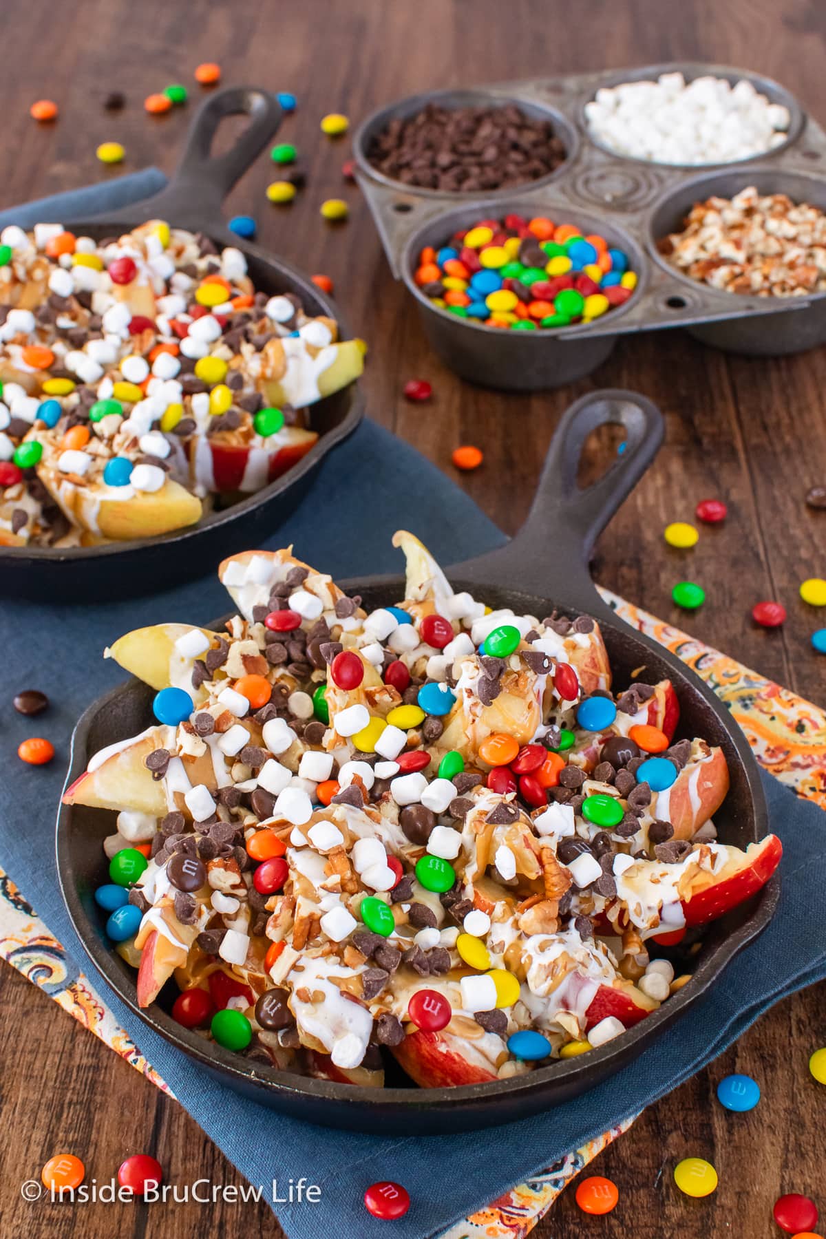 Two pans filled with apples and loaded with toppings.