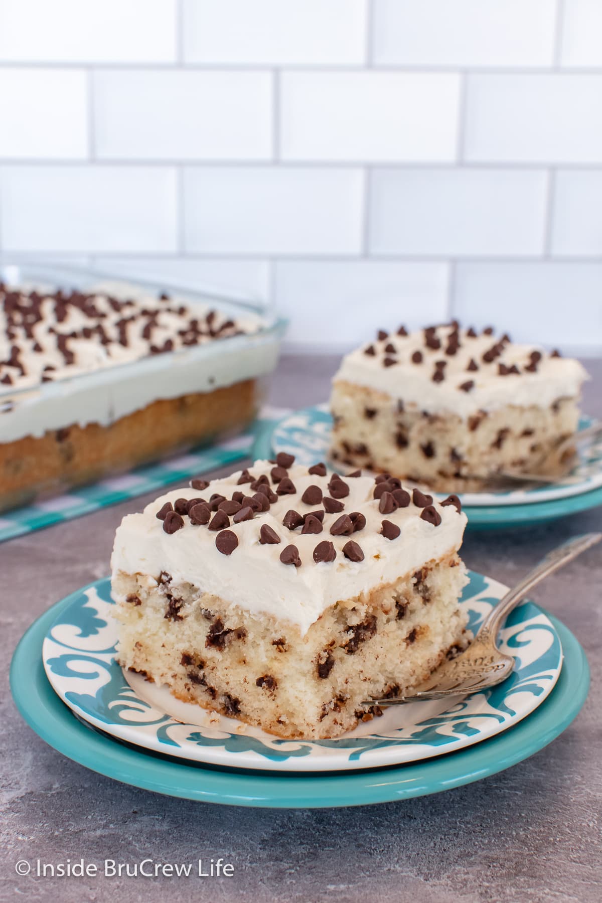 Two plates with slices of frosted cake on them.