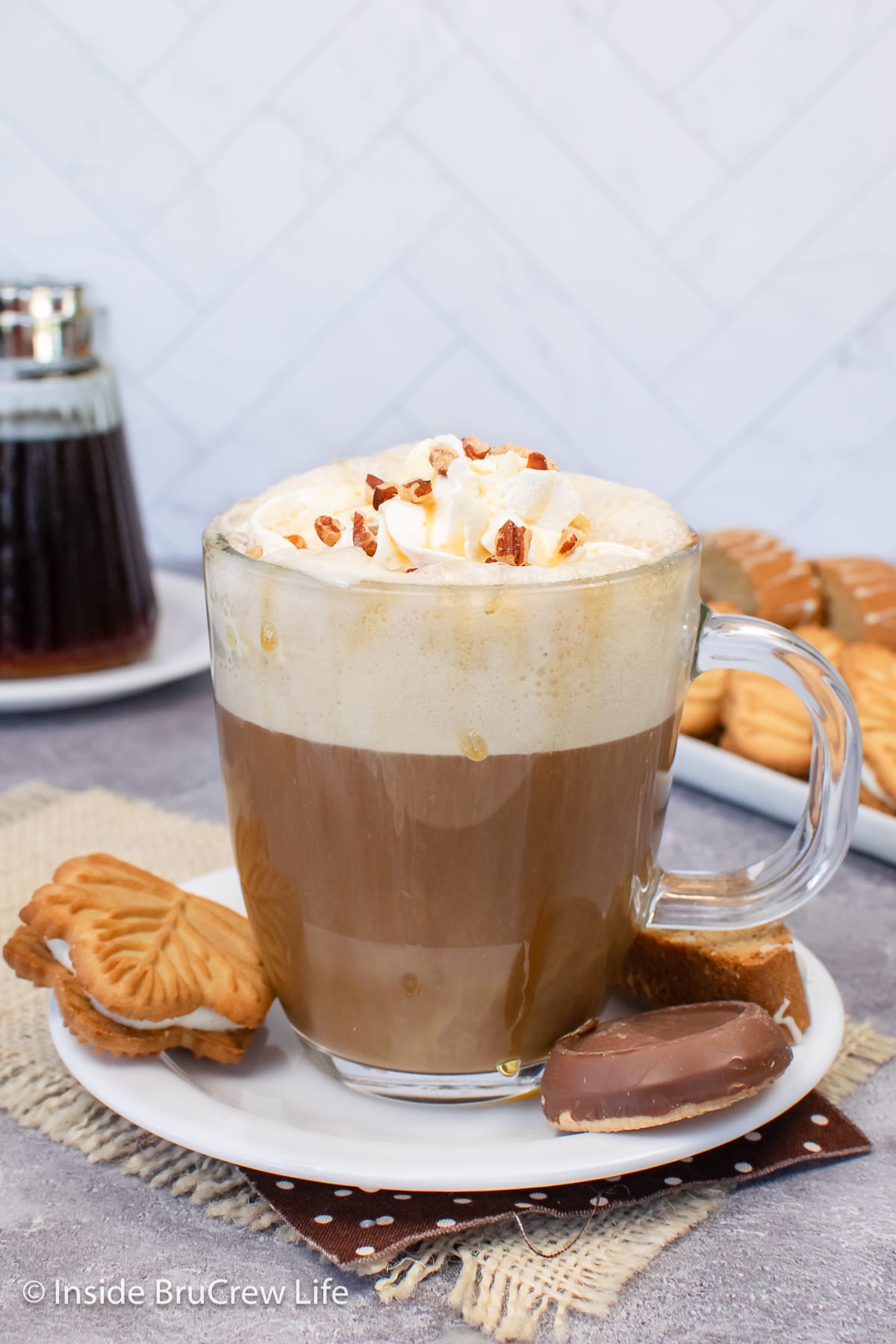 A clear cup filled with a homemade latte topped with frothed milk and whipped cream.