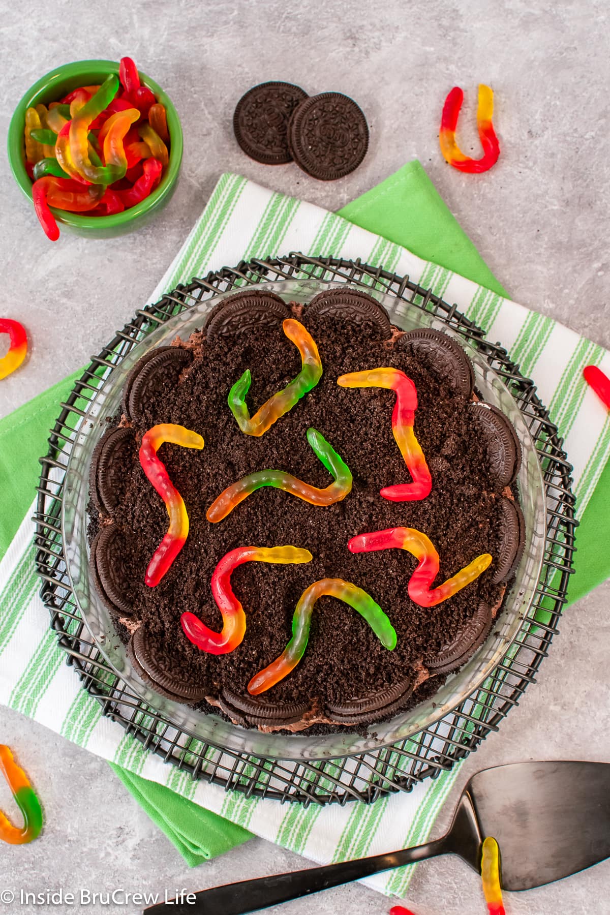 An overhead picture of a pudding pie decorated with crushed Oreos and gummy worms.