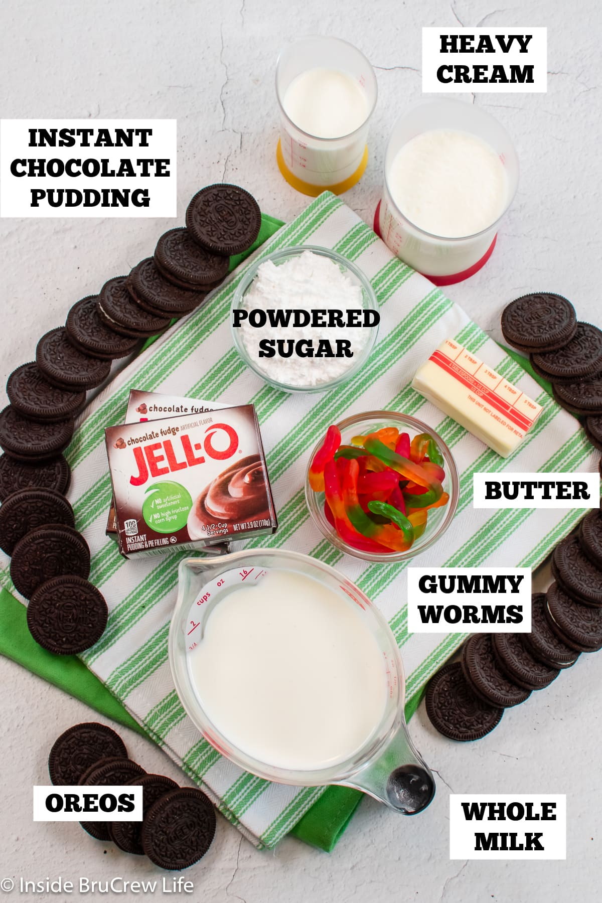 Bowls of ingredients needed to make a pudding pie with Oreos and gummy worms.