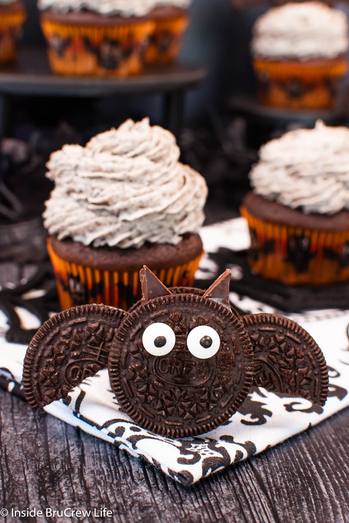 An Oreo cookie decorated like a bat with wings beside a cupcake.