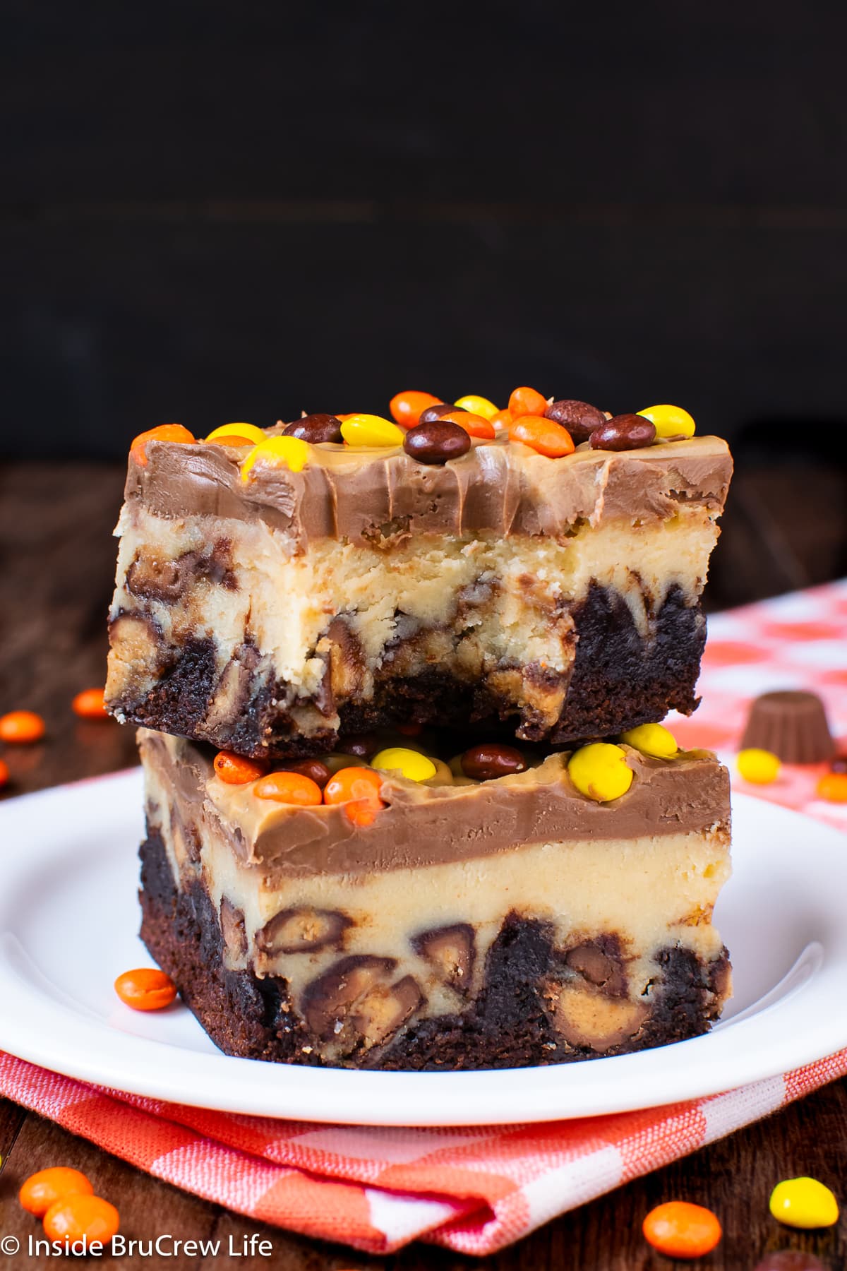 Two squares of peanut butter cheesecake brownies on a white plate.