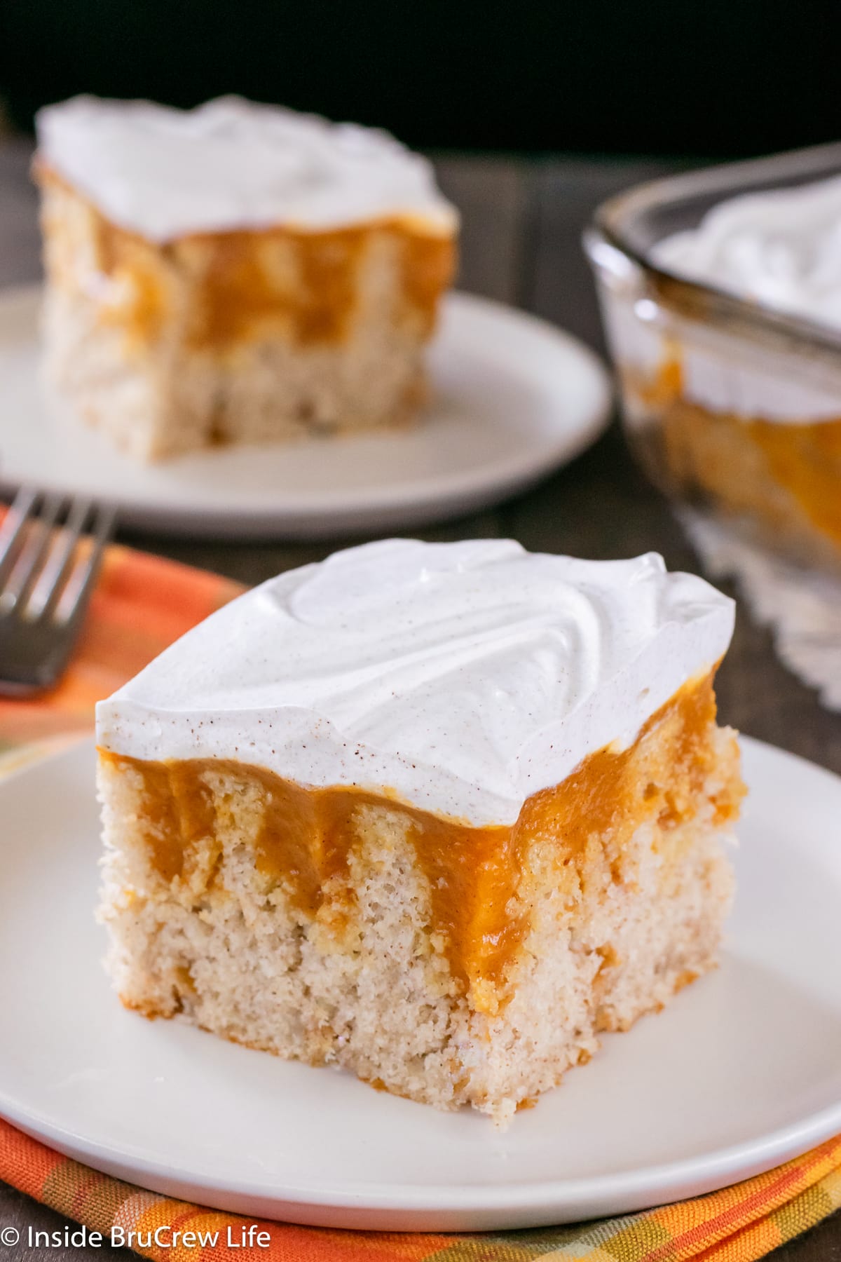 Two pieces of pumpkin pudding cake on white plates.