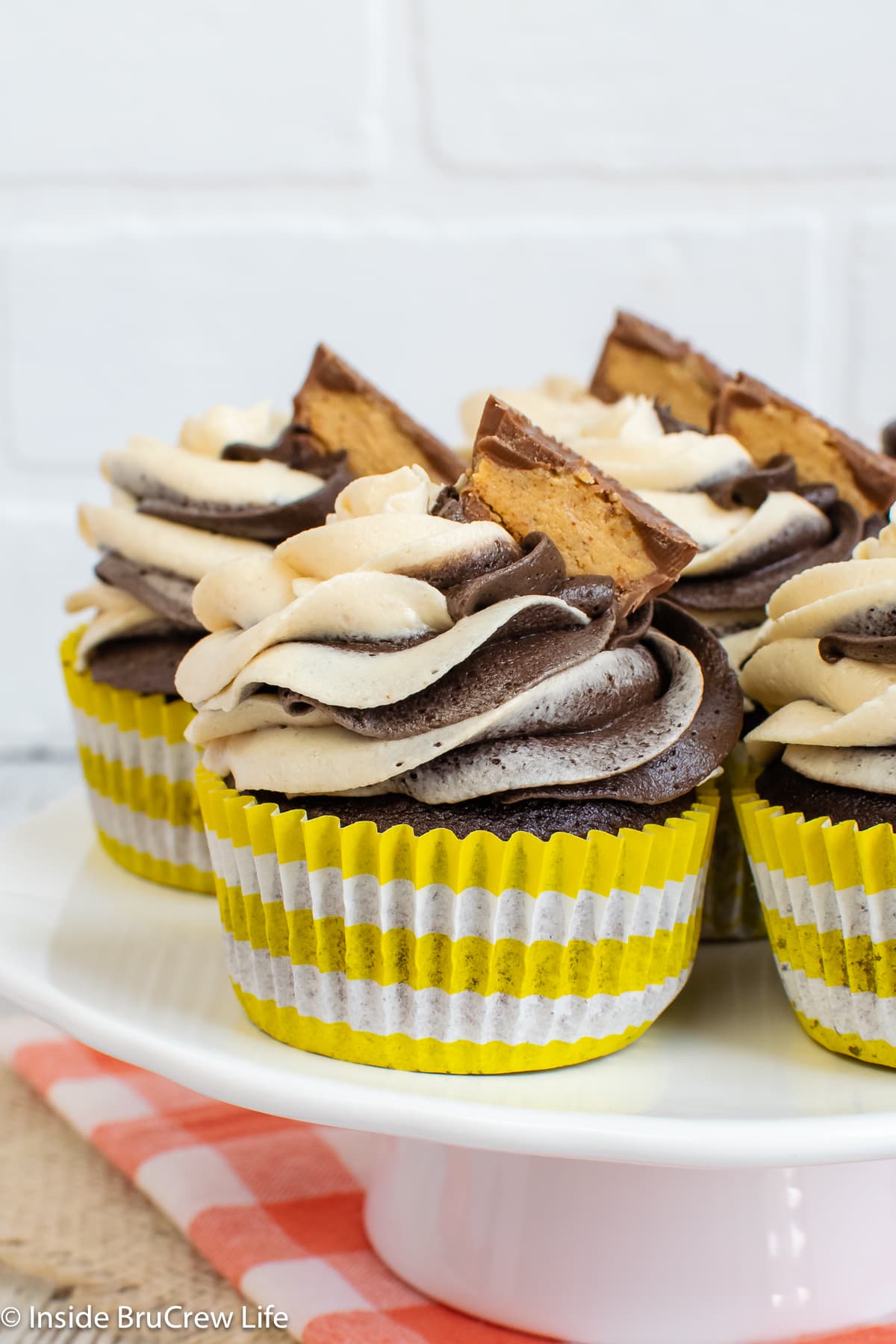 Frosted cupcakes in yellow and white liners.