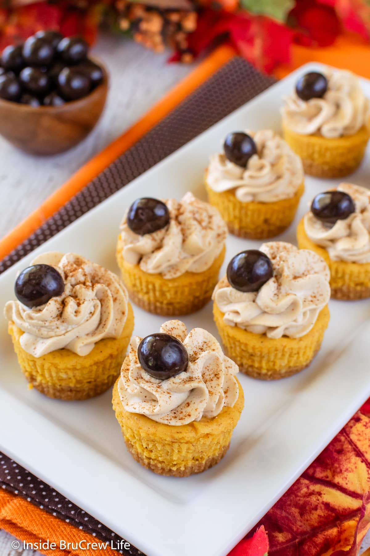 A white plate with small pumpkin cheesecakes on it.