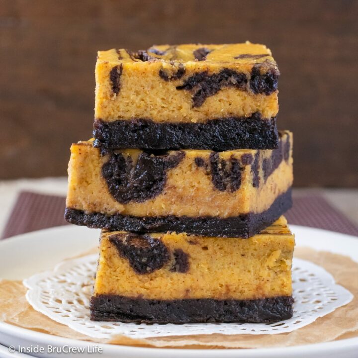 Three cheesecake brownies stacked on a plate.