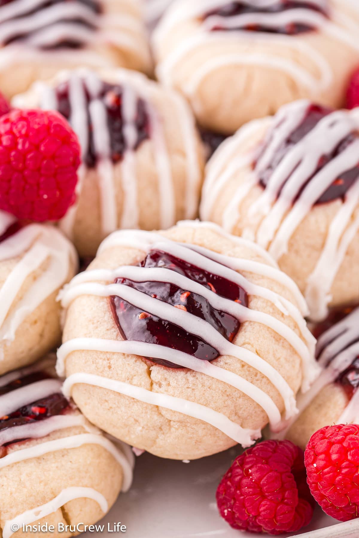 Jelly thumbprint cookies drizzled with glaze on a tray.