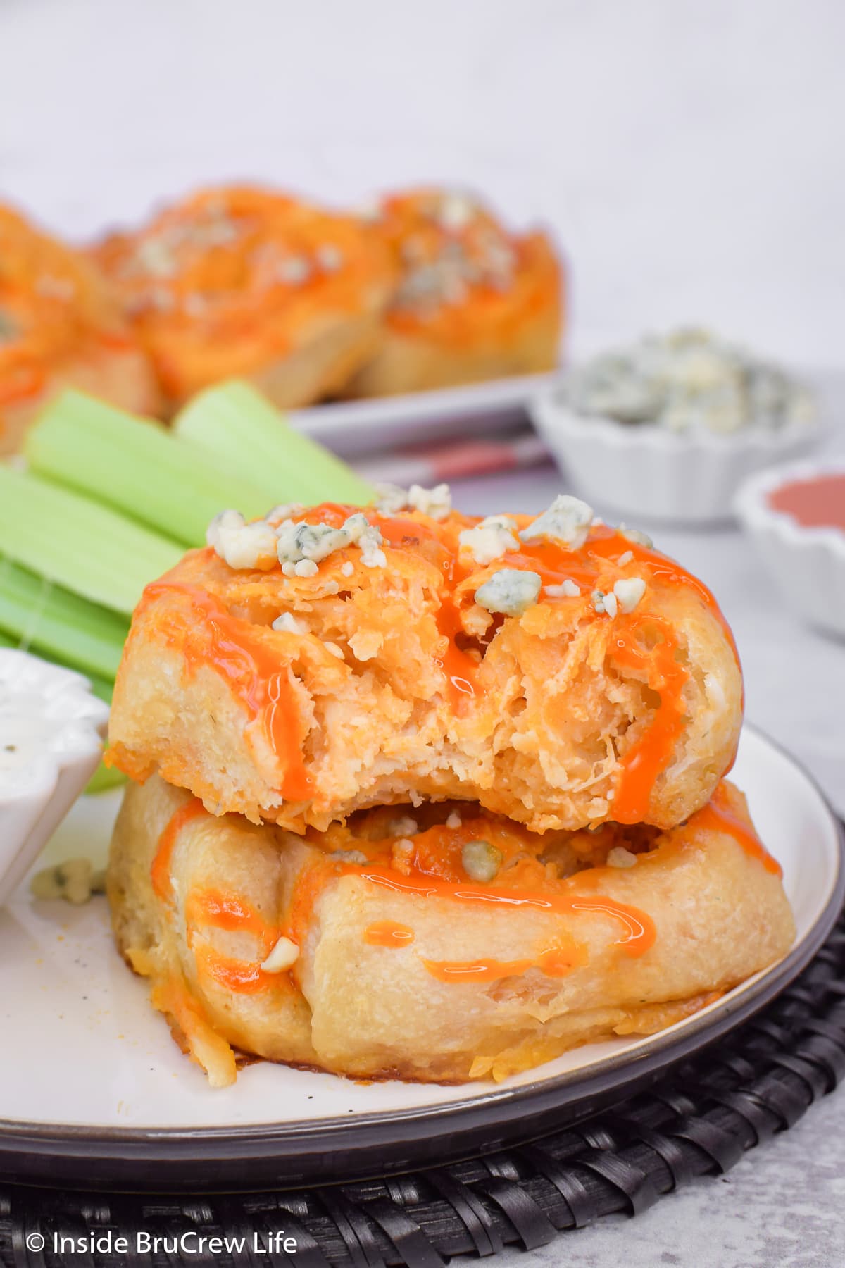 Two spicy chicken rolls stacked on a plate with a bite out of one.