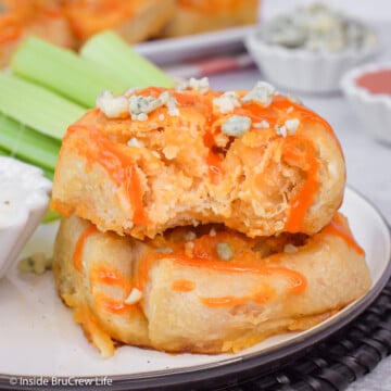 Two buffalo chicken rolls stacked on a plate with a bite out of one.